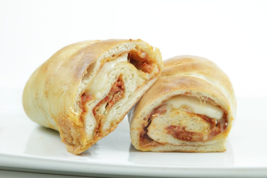 side view of pizza roll ups  showing the filling on a white plate 