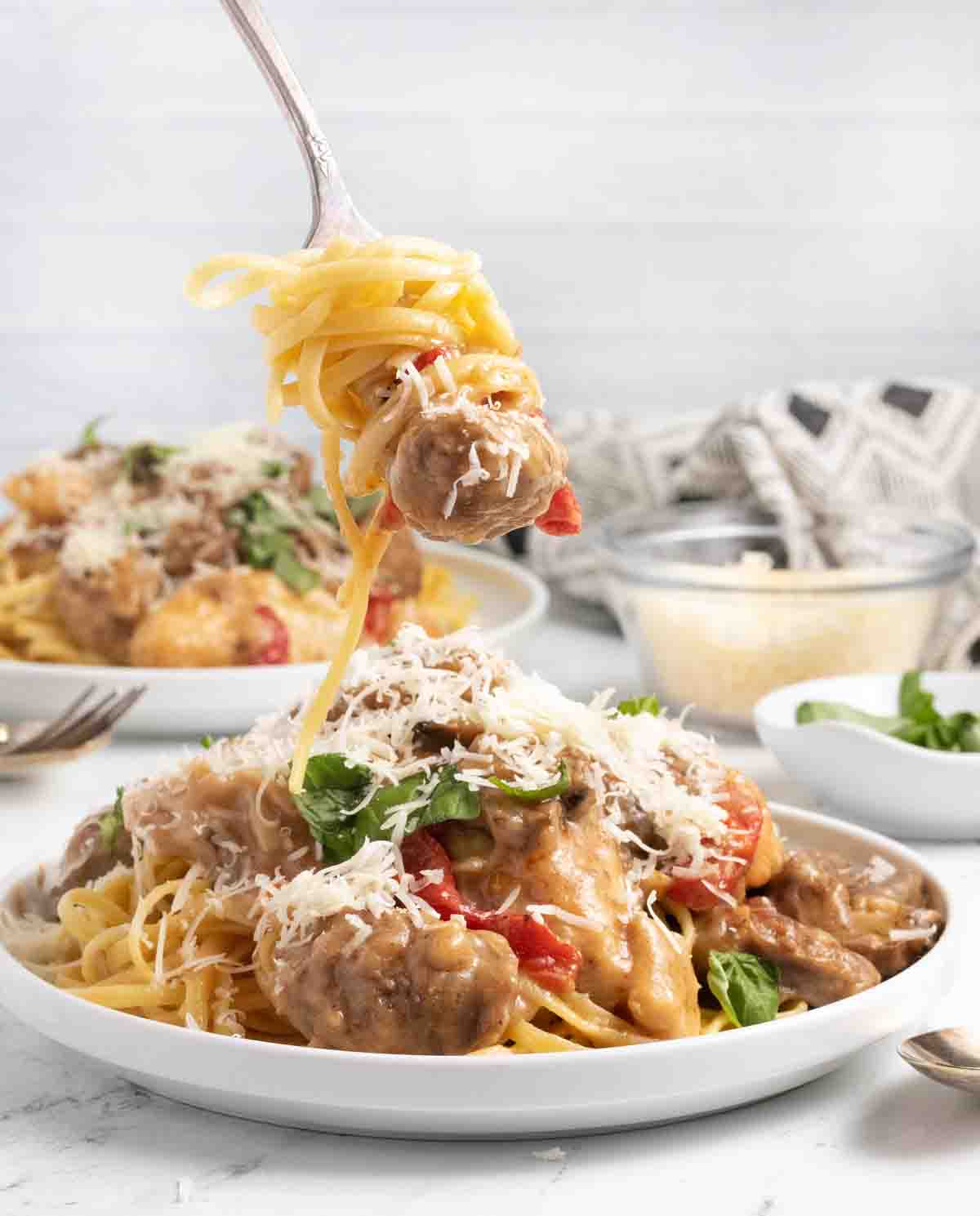 tuscan chicken and shrimp over pasta on a white plate with a forkful of pasta lifted out