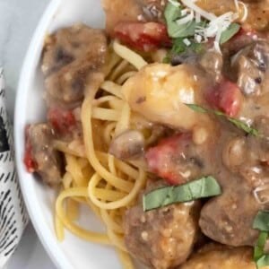 partial view of Tuscan chicken and sausage on a white plate