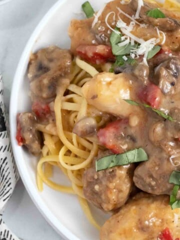 partial view of Tuscan chicken and sausage on a white plate