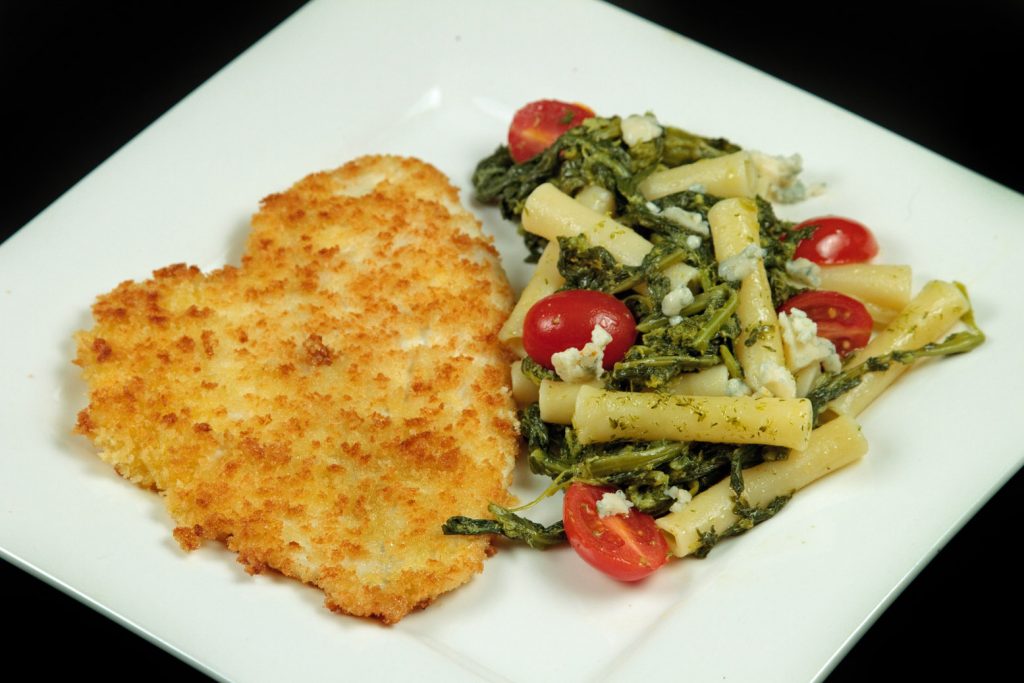 Panko breaded flounder with broccoli rabe pasta on a white plate