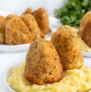 turkey croquettes on a bed of mashed potatoes on a white plate
