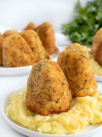 turkey croquettes on a bed of mashed potatoes on a white plate
