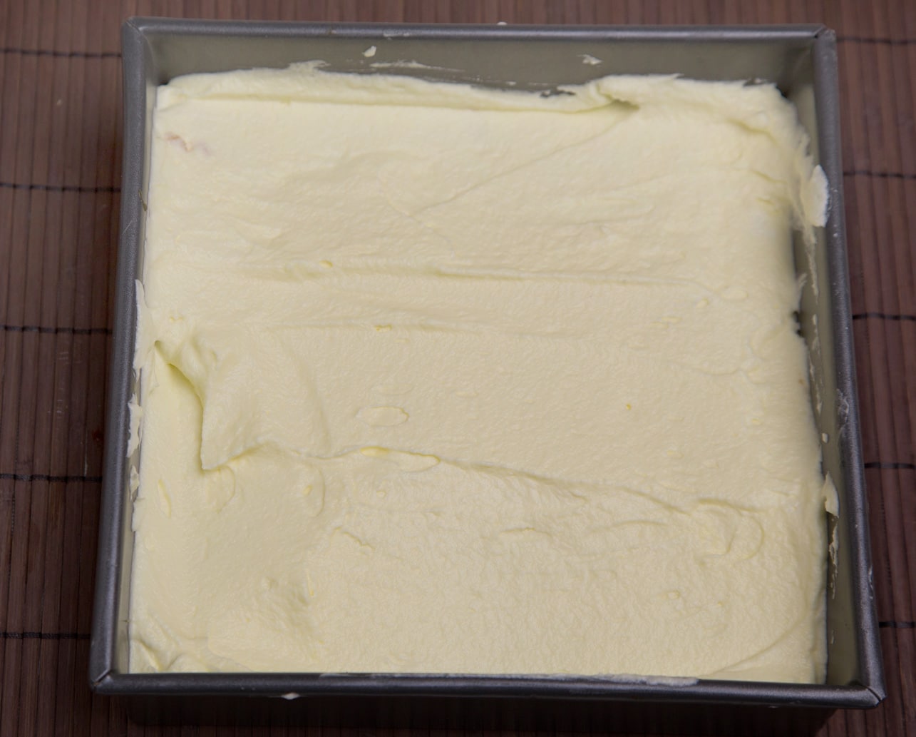 layer of tiramisu cream on top of ladyfingers in pan