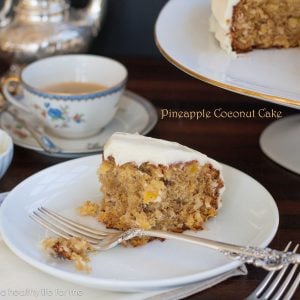 half-eaten slice of pineapple coconut cake on a white plate with a fork and teacup in the background