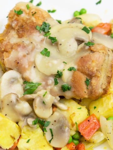 chicken topped with mushroom sauce on a bed of potatoes and carrots