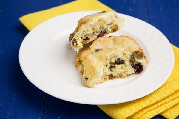 meyer lemon scone sitting on a white plate with a yellow napkin under it on a blue background