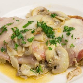side view of Chicken Sorrento garnished with parsley on a white plate