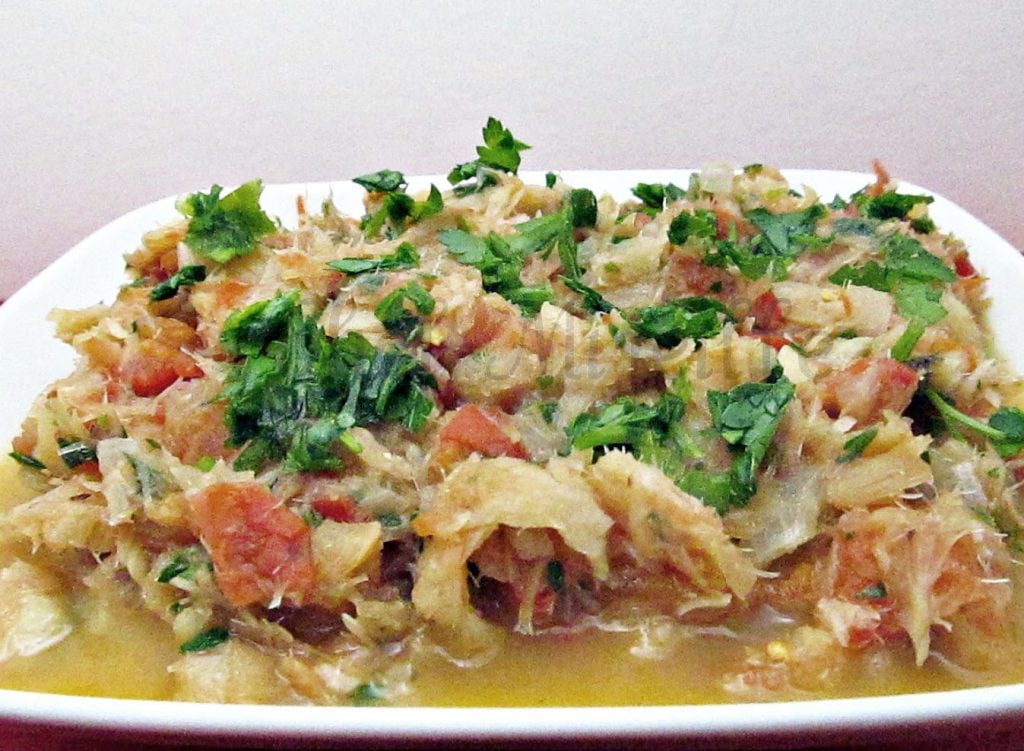 italian baccala on a white platter garnished with rough cut parsley