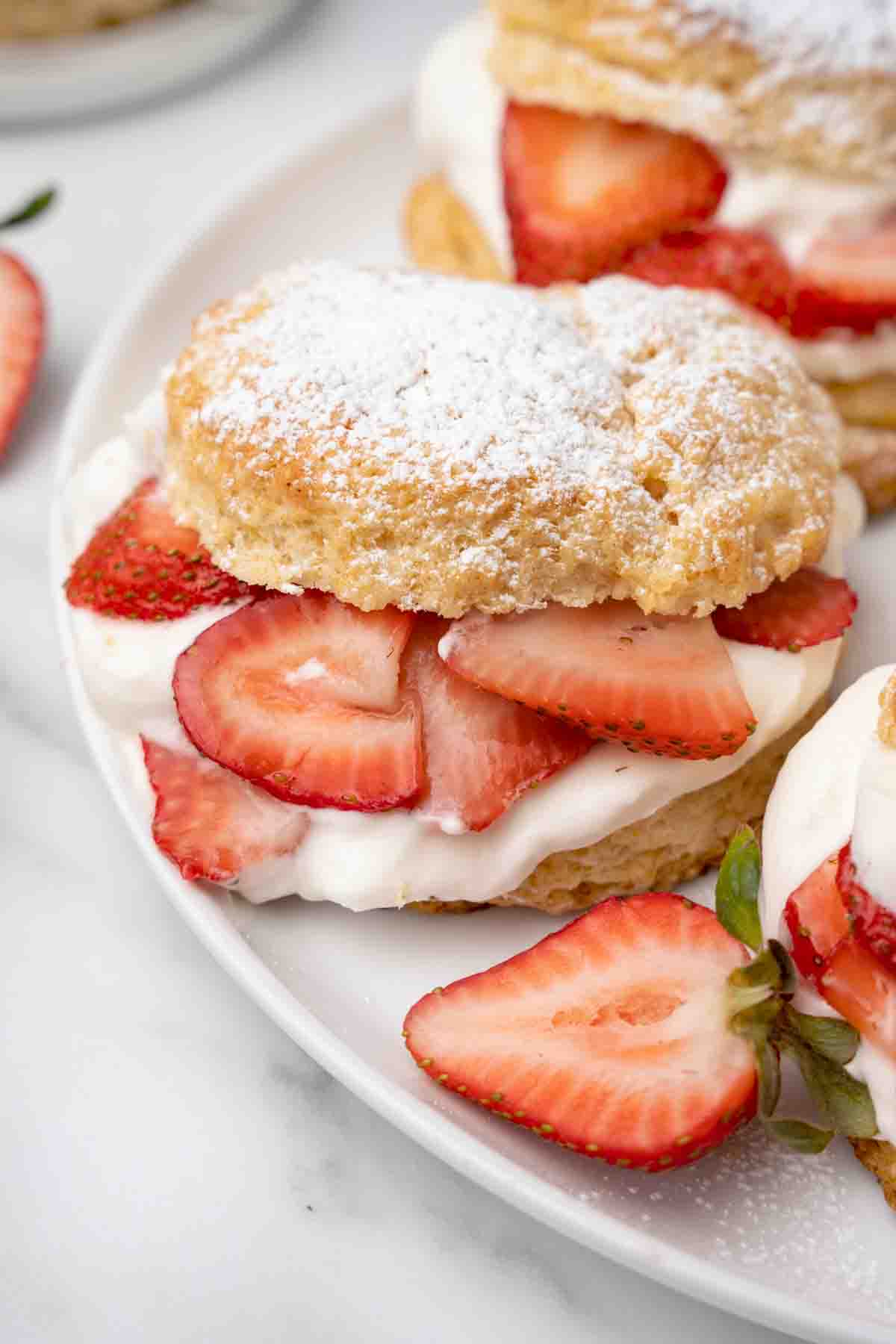 individual strawberry shortcake on a white plate with strawberries around the plate