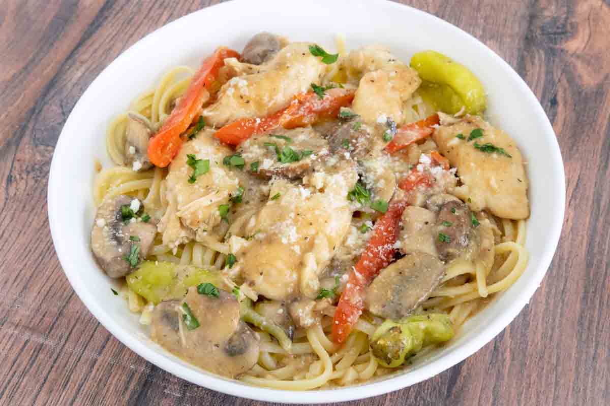 Chicken tuscano with pasta in white bowl.