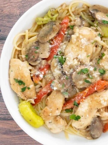 Chicken tuscano with pasta in white bowl.