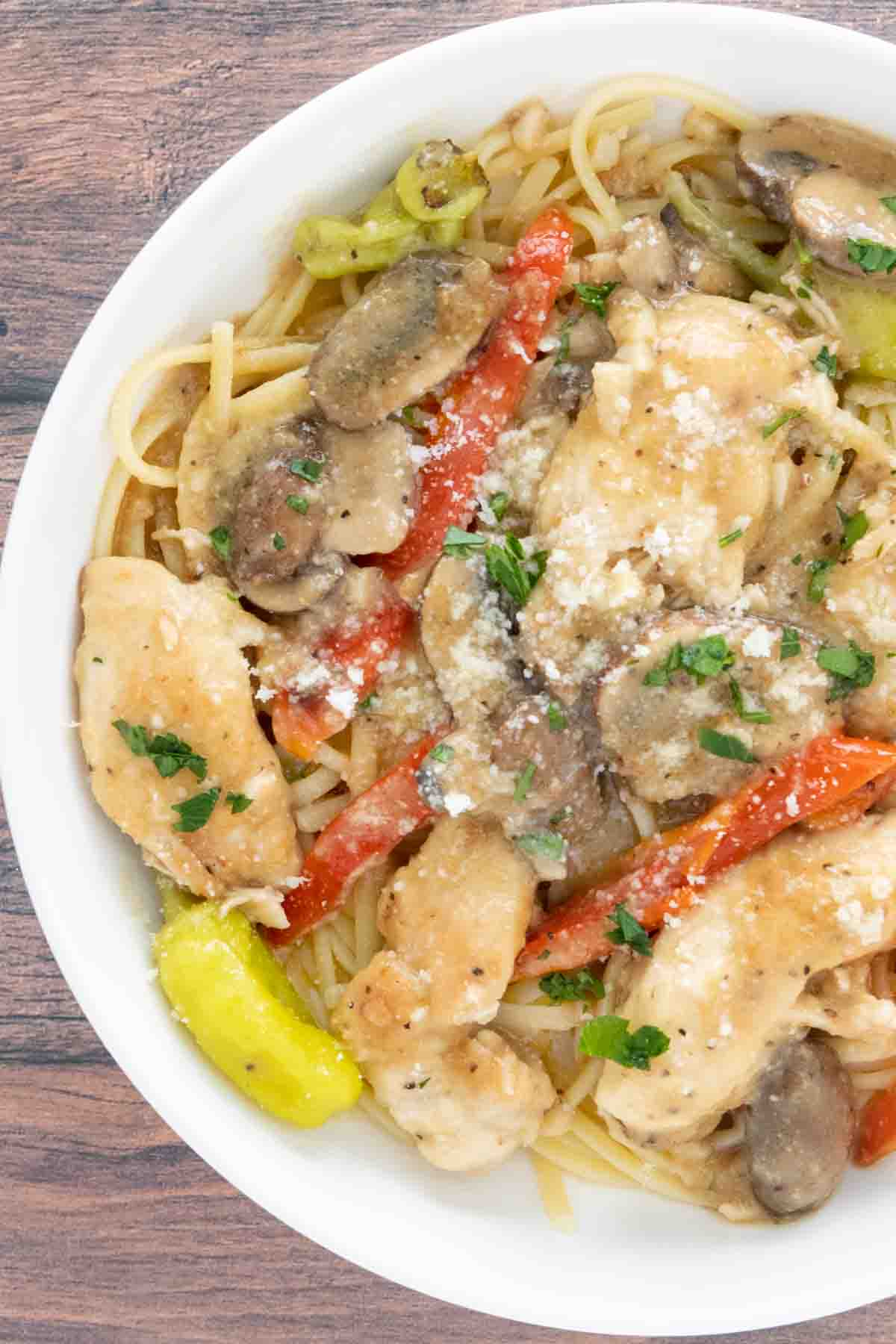 Chicken tuscano with pasta in white bowl.