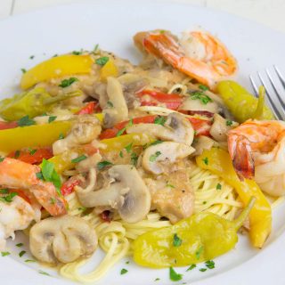 chicken and shrimp Toscano over pasta on a white plate