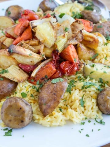 White platter with saffron rice and root vegetables made paella st yle on a wooden cutting board