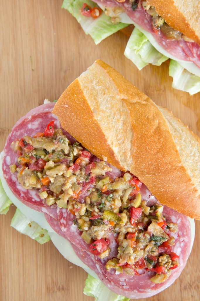 italian meats and cheese with Caponata on a section of a baguette with the top on the side