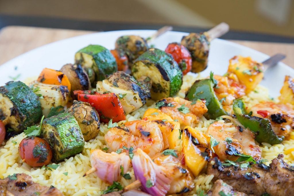 Moroccan Vegetable Skewers, Sweet and Spicy Shrimp Skewers on a bed of rice on a white plate