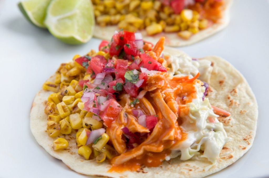 side view of Buffalo Chicken Taco with lime slices and part of another taco in the background