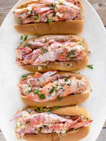 4 lobster rolls on a white platter.