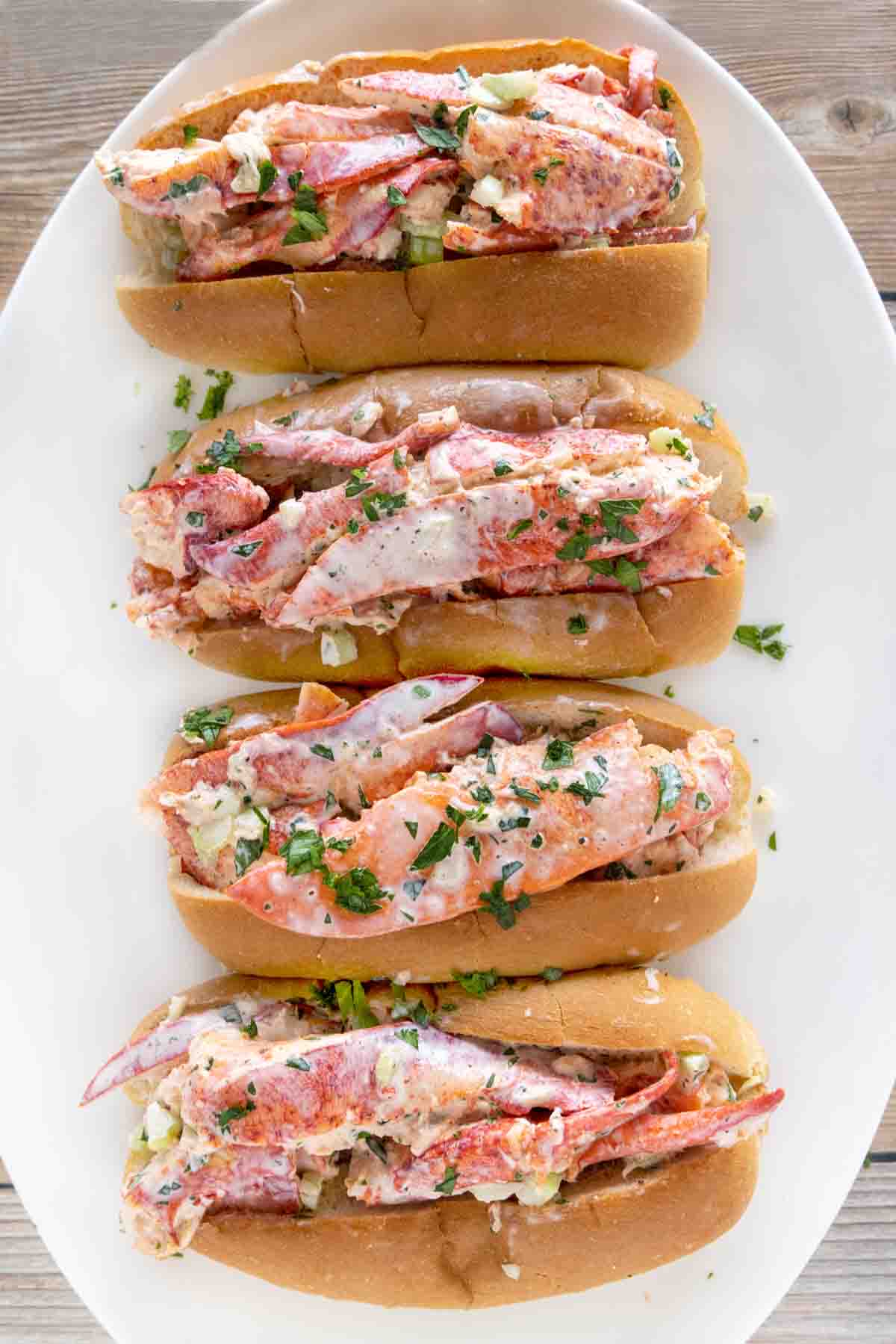 4 lobster rolls on a white platter.