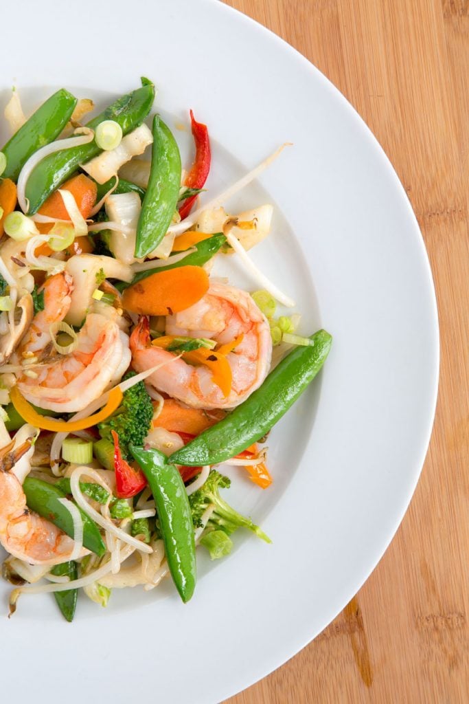 overhead partial view Shrimp stir fry on a white plate