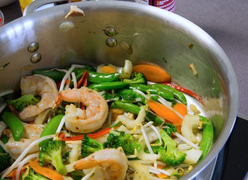 partial view of shrimp and stir fry vegetables in a stock pot