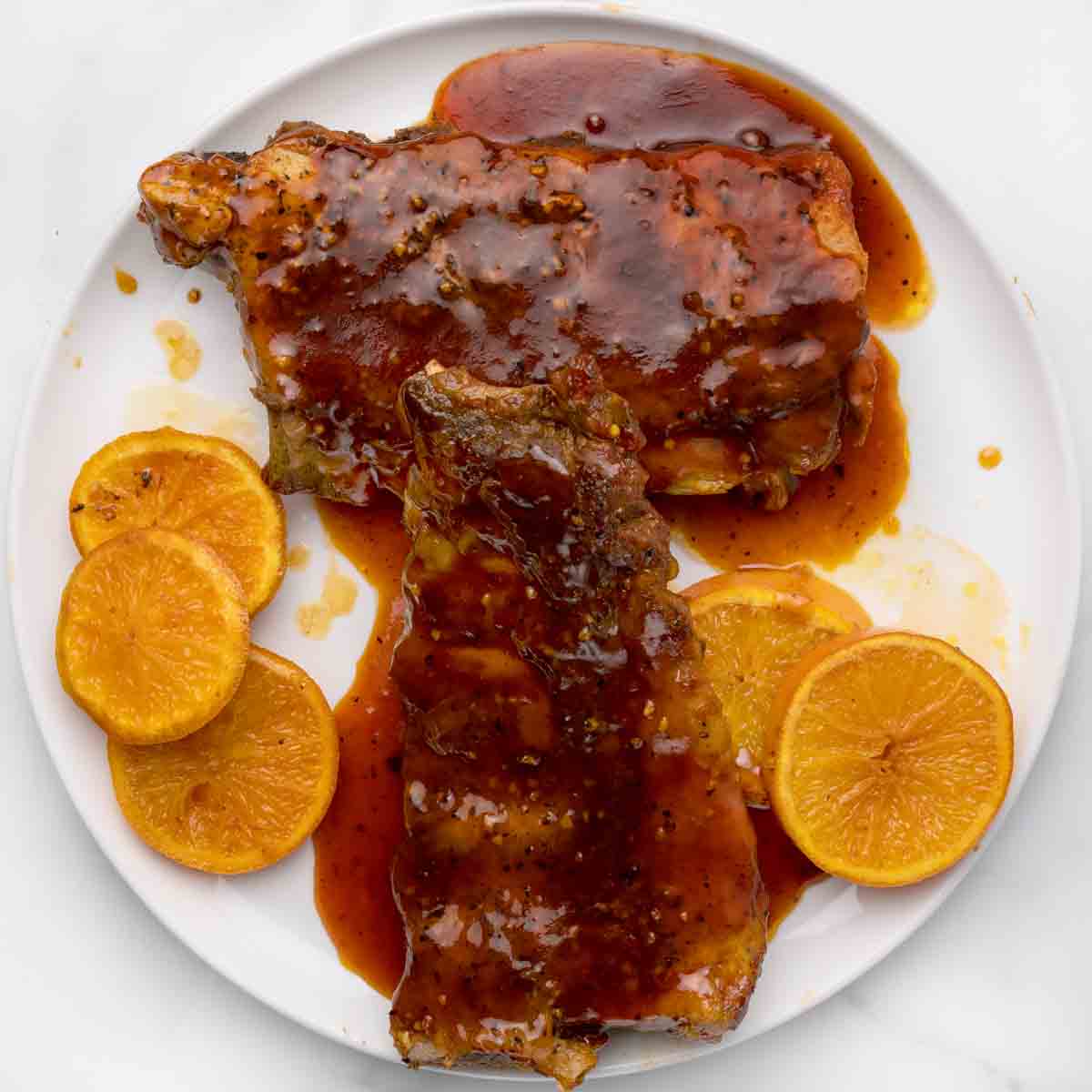 overhead view of 2 half racks of bbq sauced baby back ribs on white plate