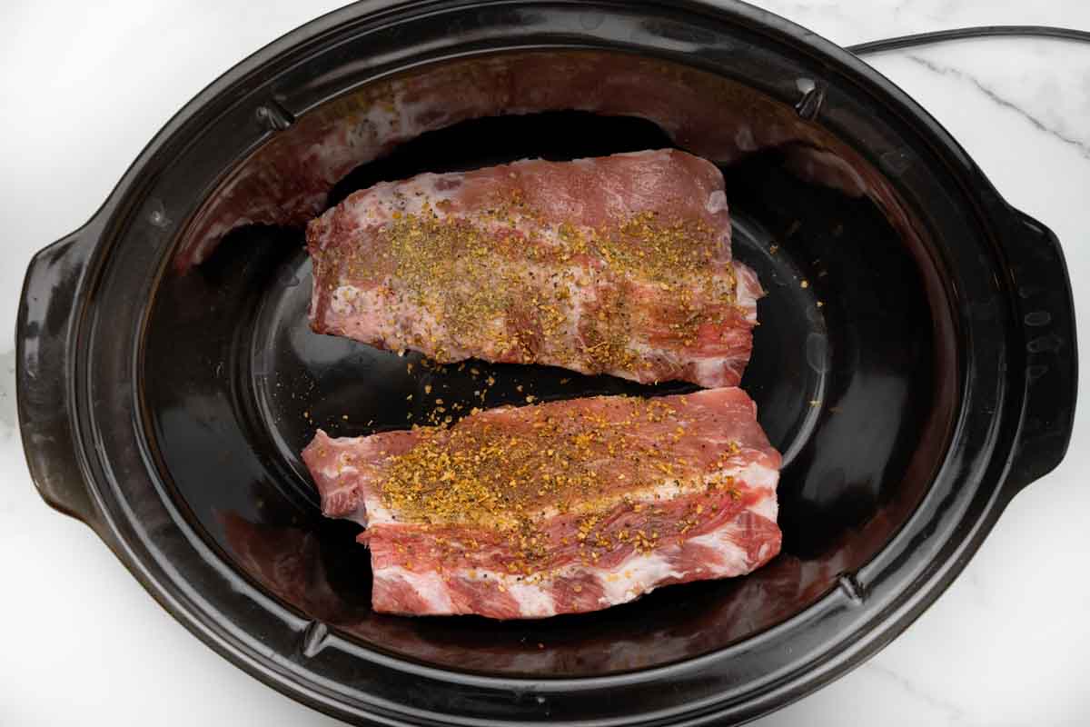 seasoned half racks of ribs in slow cooker