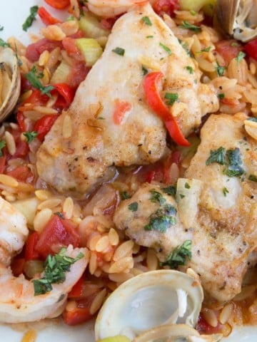 overhead shot of Chicken and Shrimp Orzo Paella on a white plate