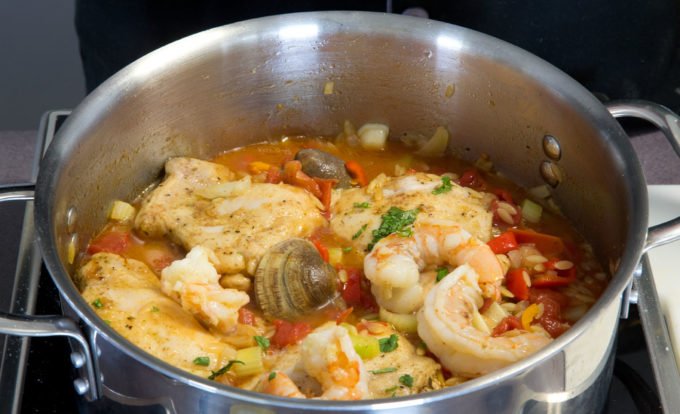 stainless steel pot with chicken and shrimp orzo paella as it cooks in the pot
