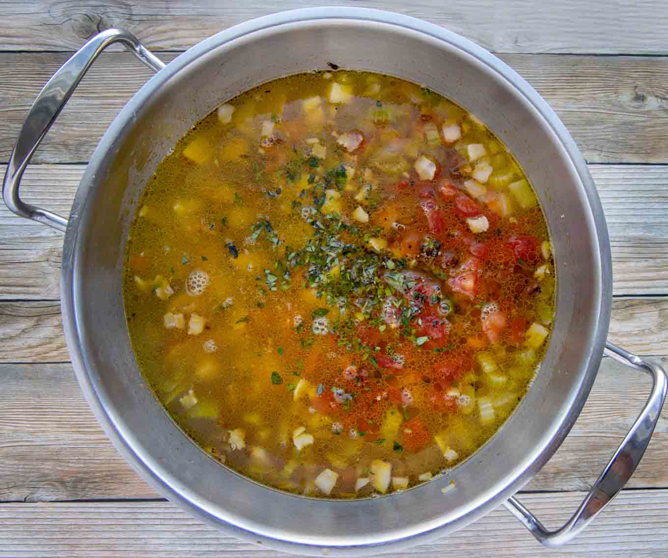 stock and tomatoes added to the pot