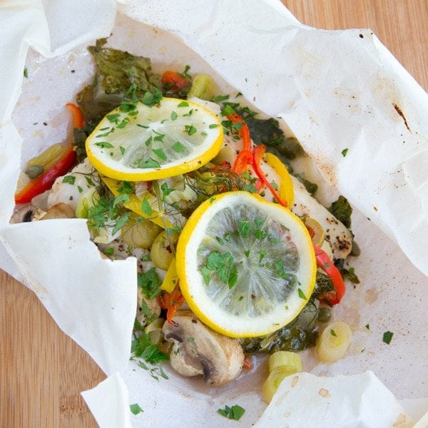 overhead view of Red Snapper topped with vegetables, herbs and lemon baked in parchment, showing package opened