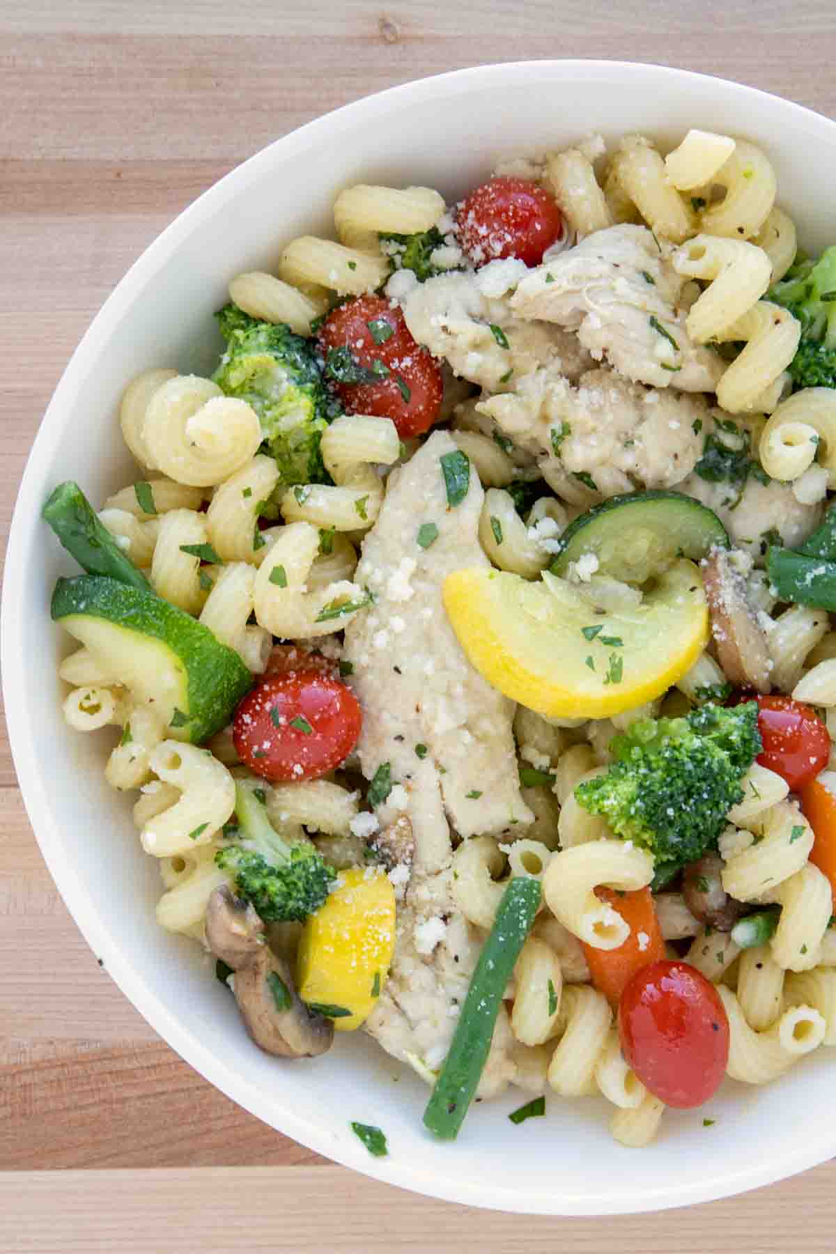 overhead partial image of chicken primavera in a white bowl