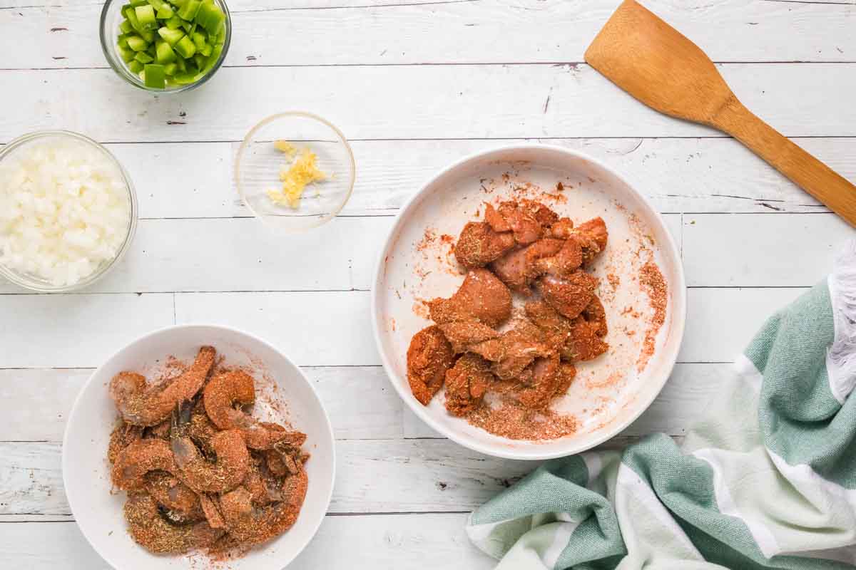 seasoned chicken and shrimp in white bowls