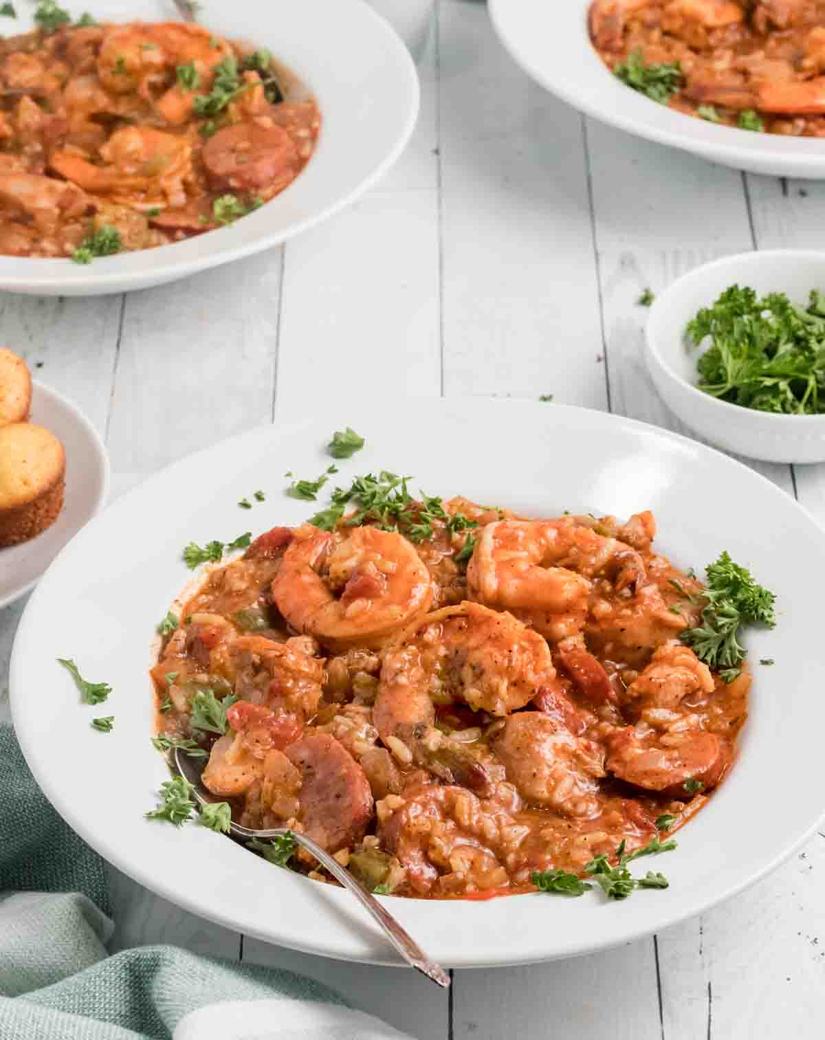 skillet jambalaya in a white bowl with other bowls of jambalaya in the background