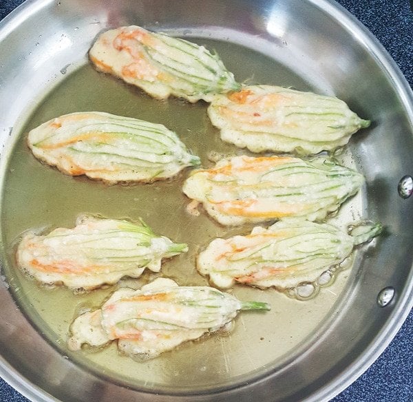 egg battered stuffed blossoms in a saute pan with hot oil