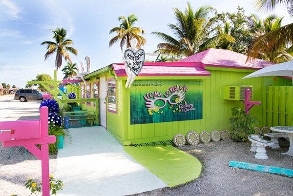 chartreuse color building with hot pink accents and palm trees in the background in Matlacha 