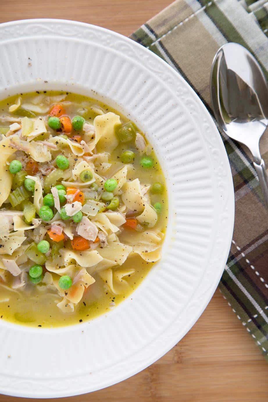 turkey noodle soup in a white bowl.