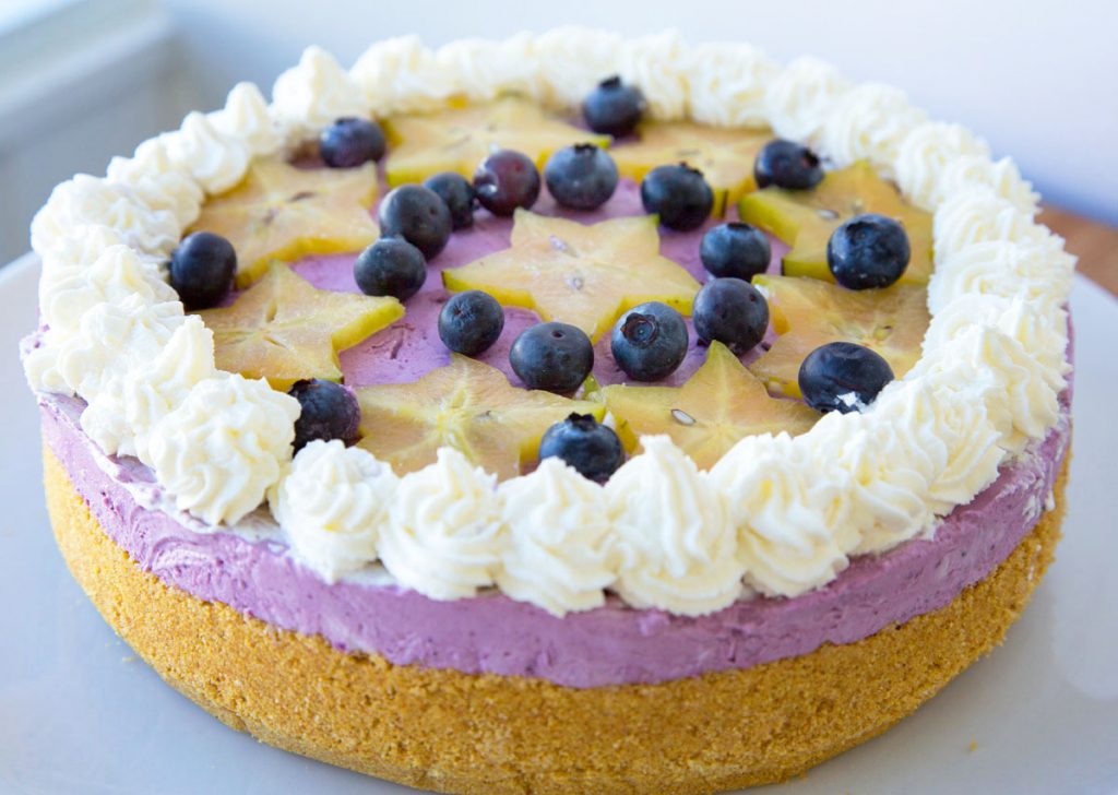 side view of a blueberry cream pie with star fruit slices and blueberries on top