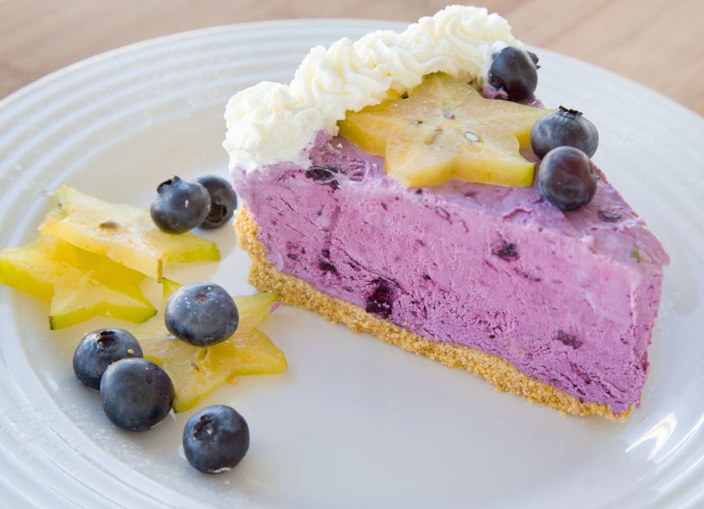 slice of a blueberry cream pie  on a white plate with star fruit slices and blueberries 