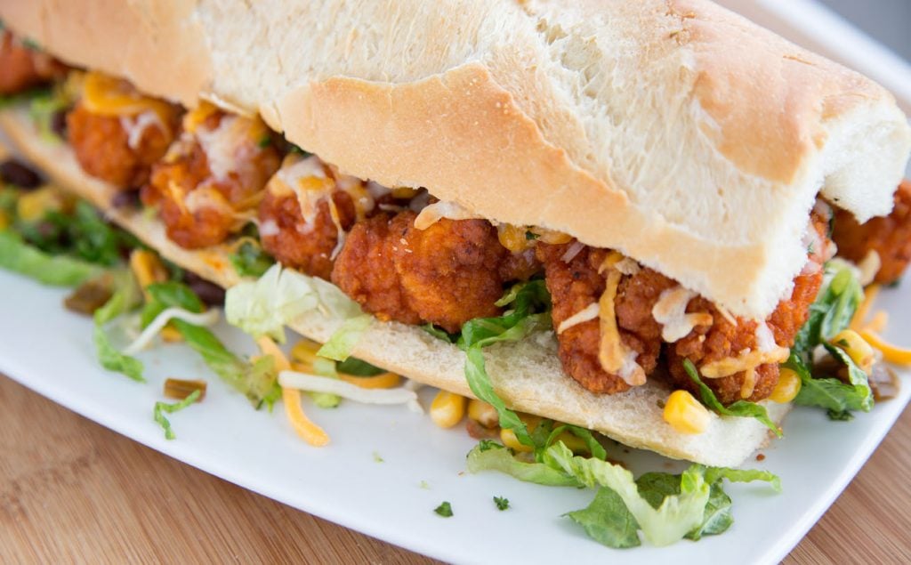 side view of a buffalo chicken po boy  on a white plate