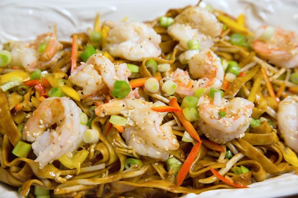 Chinese style dan dan noodles with shrimp on a white plate