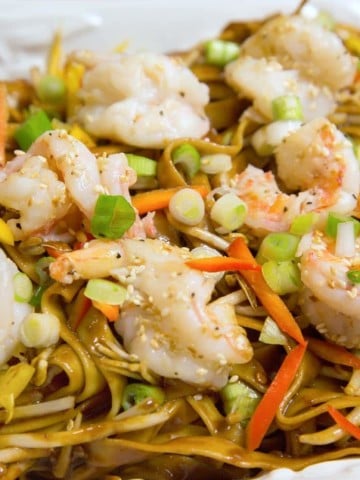 Chinese style dan dan noodles with shrimp on a white plate