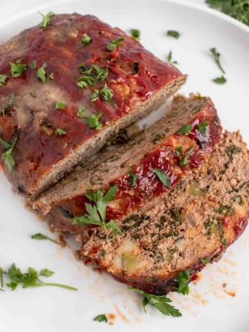 overhead view of sliced meatloaf on a white platter