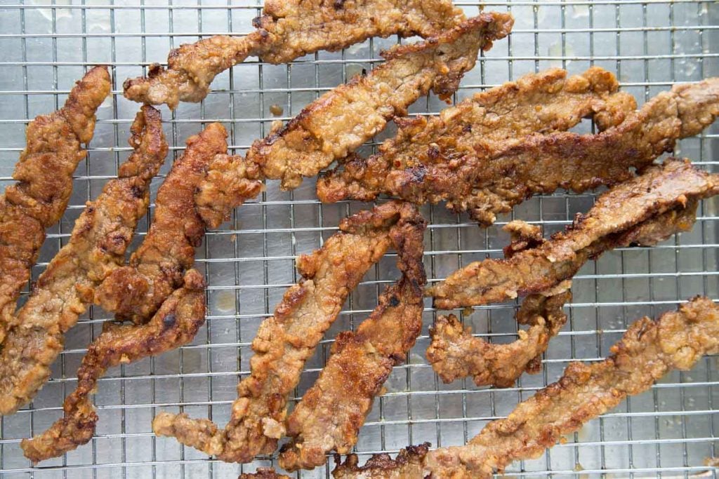 cooked beef strips on a wire grate