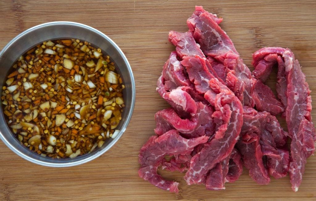 marinade and sliced raw beef on a cutting board