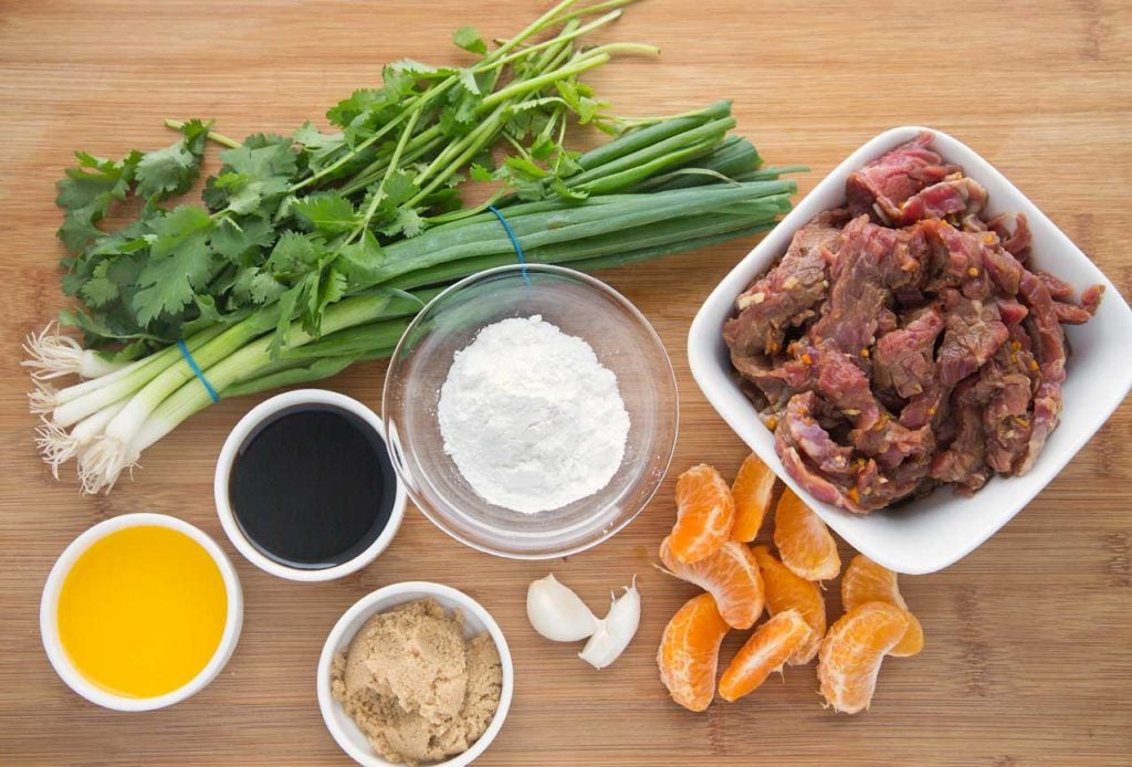 ingredients to make tangerine beef on a wooden cutting board