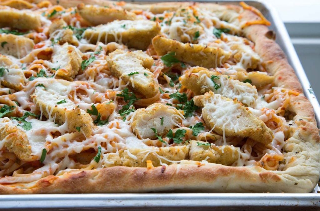 side view of a cooked sheet pan chicken parm pizza