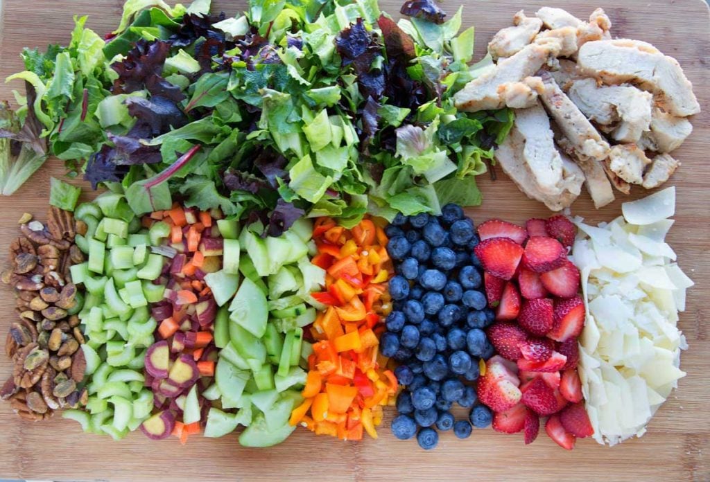 overhead view of ingredients to make the perfect dinner salad on a wooden cutting board