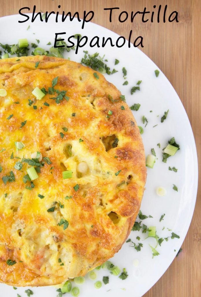 overhead partial view of Spanish Shrimp tortilla on white plate garnished with scallions and parsley